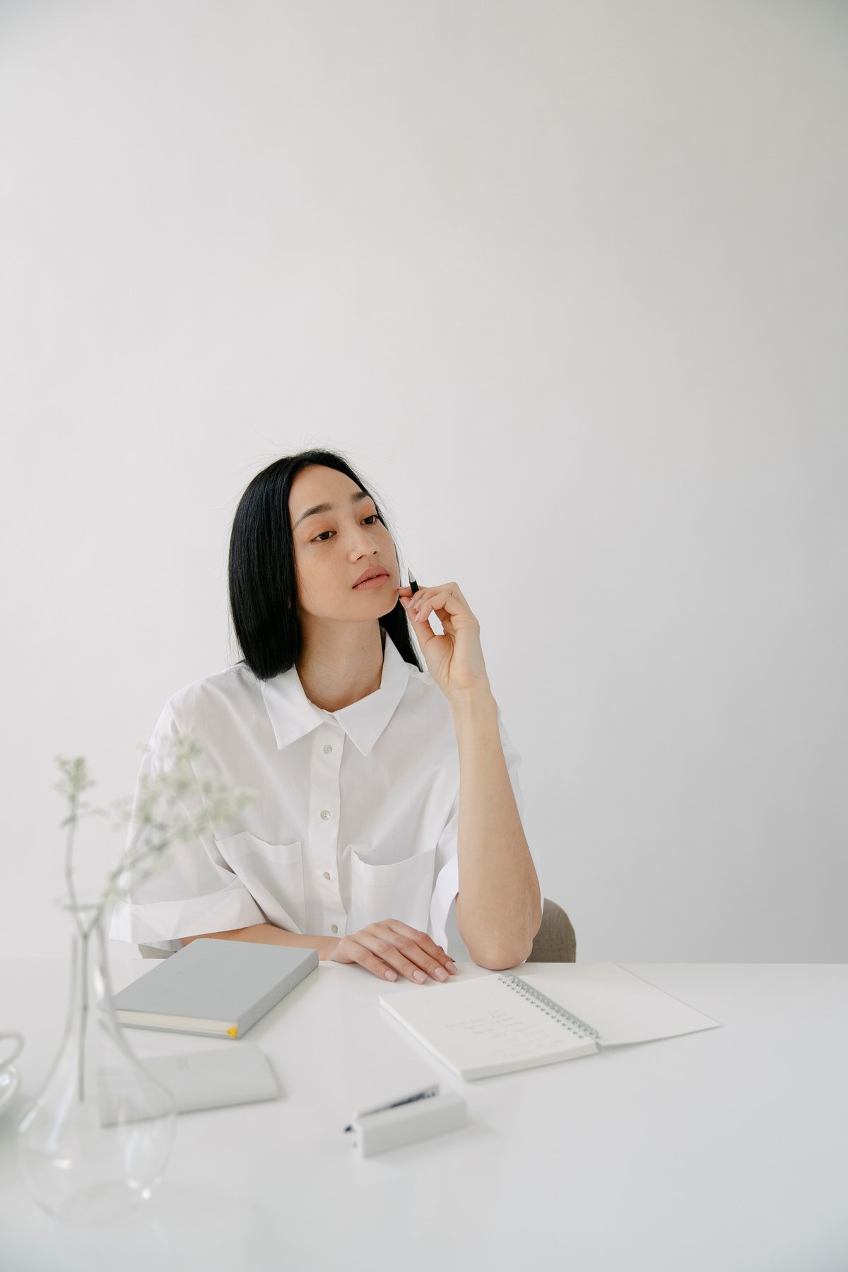 Thoughtful Asian employee with agendas at office table